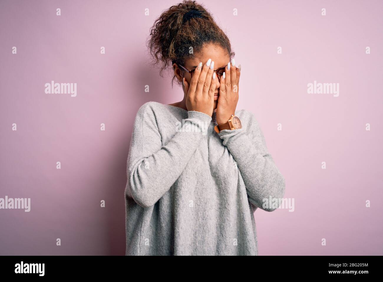 Young beautiful african american girl wearing sweater and glasses over pink background rubbing eyes for fatigue and headache, sleepy and tired express Stock Photo