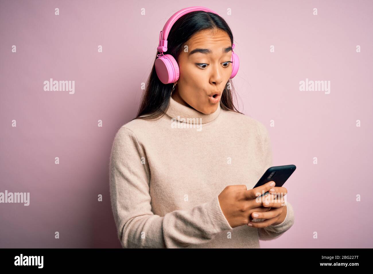 Young beautiful asian woman listening to music using smartphone and