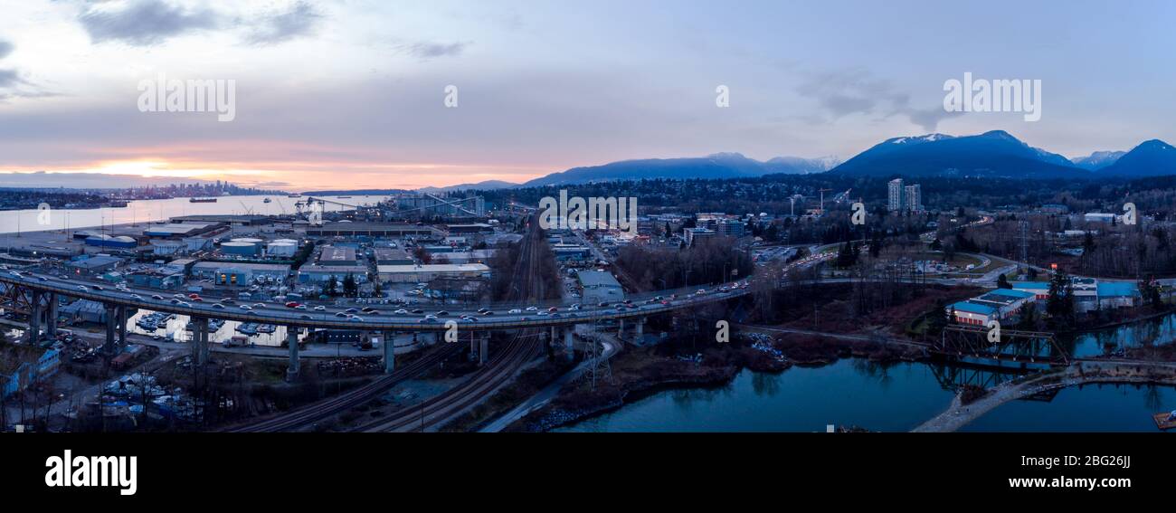 Aerial drone shot of commuter traffic on the Second Narrows bridge and the industrial port facilities in Vancouver, BC, Canada at sunset. Stock Photo