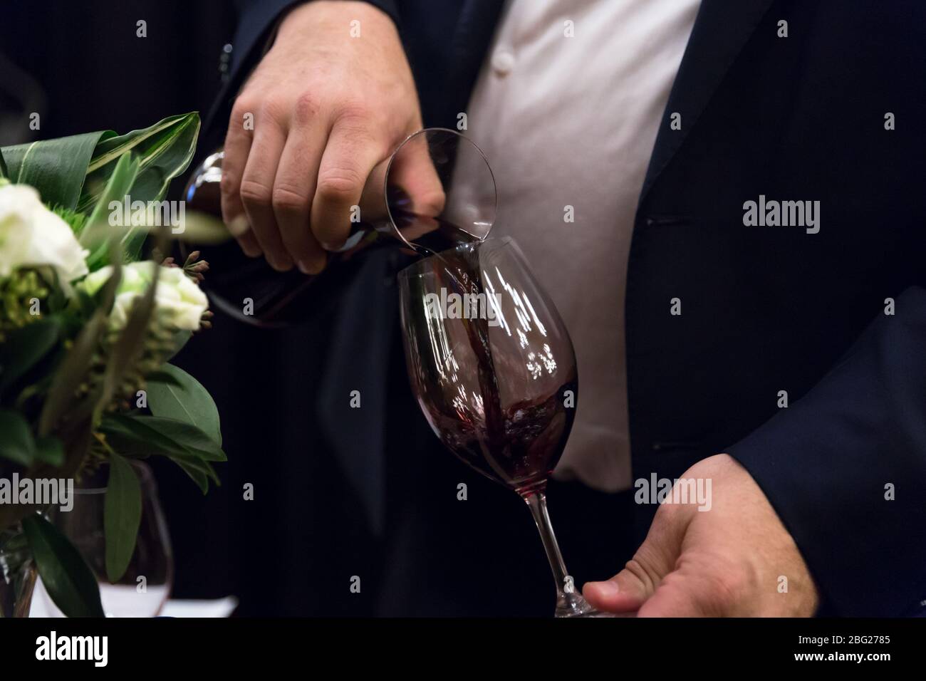 Closeup of a man pouring red wine into a wine glass. Stock Photo