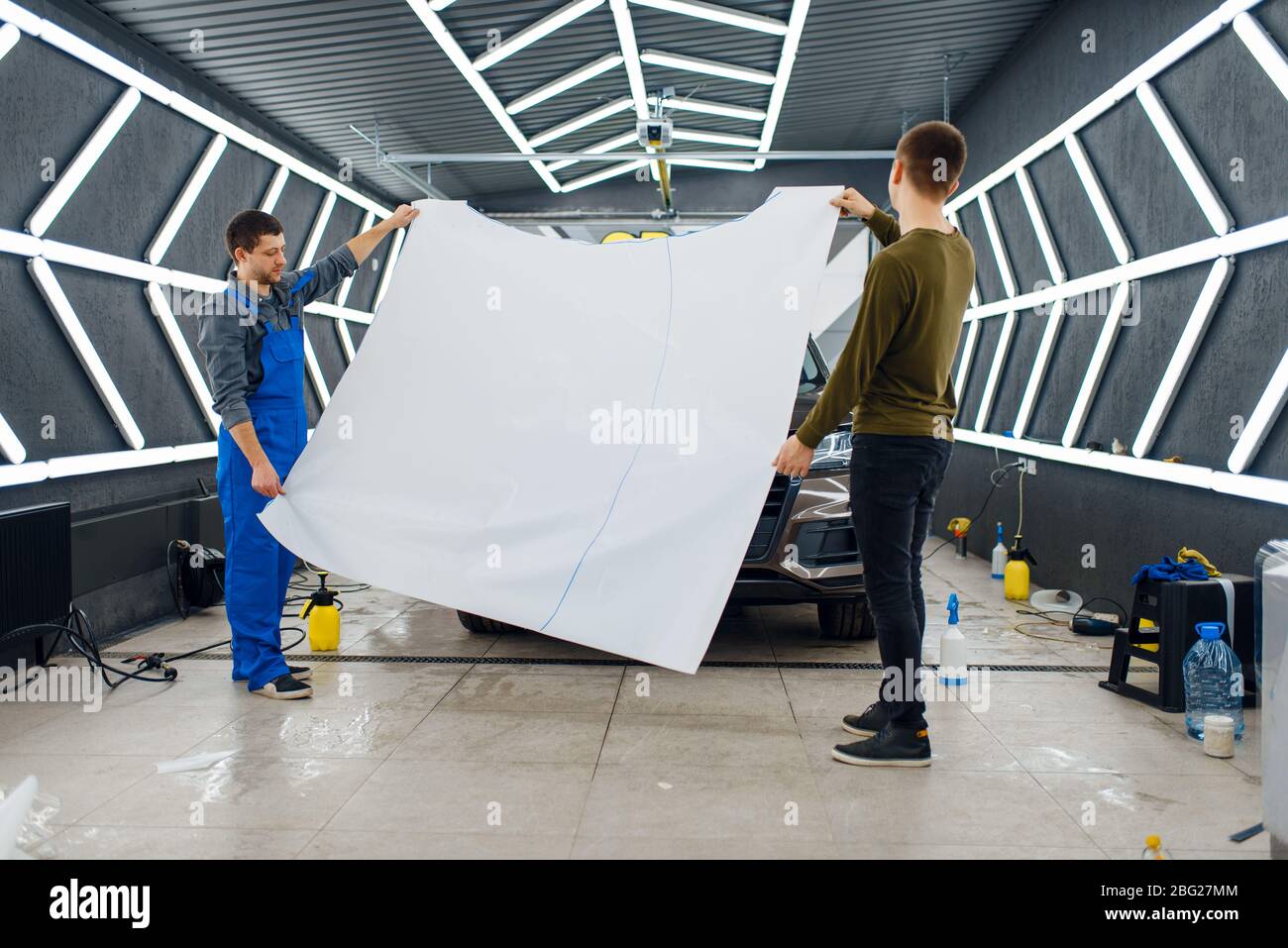 Workers holds hood template of car protection film Stock Photo Alamy