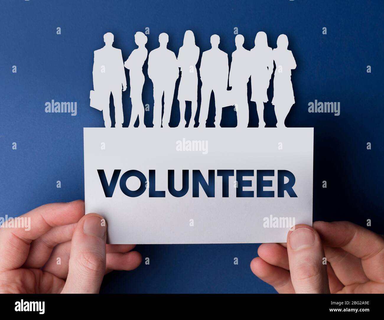 Hands holding a volunteer white card business team people sign Stock
