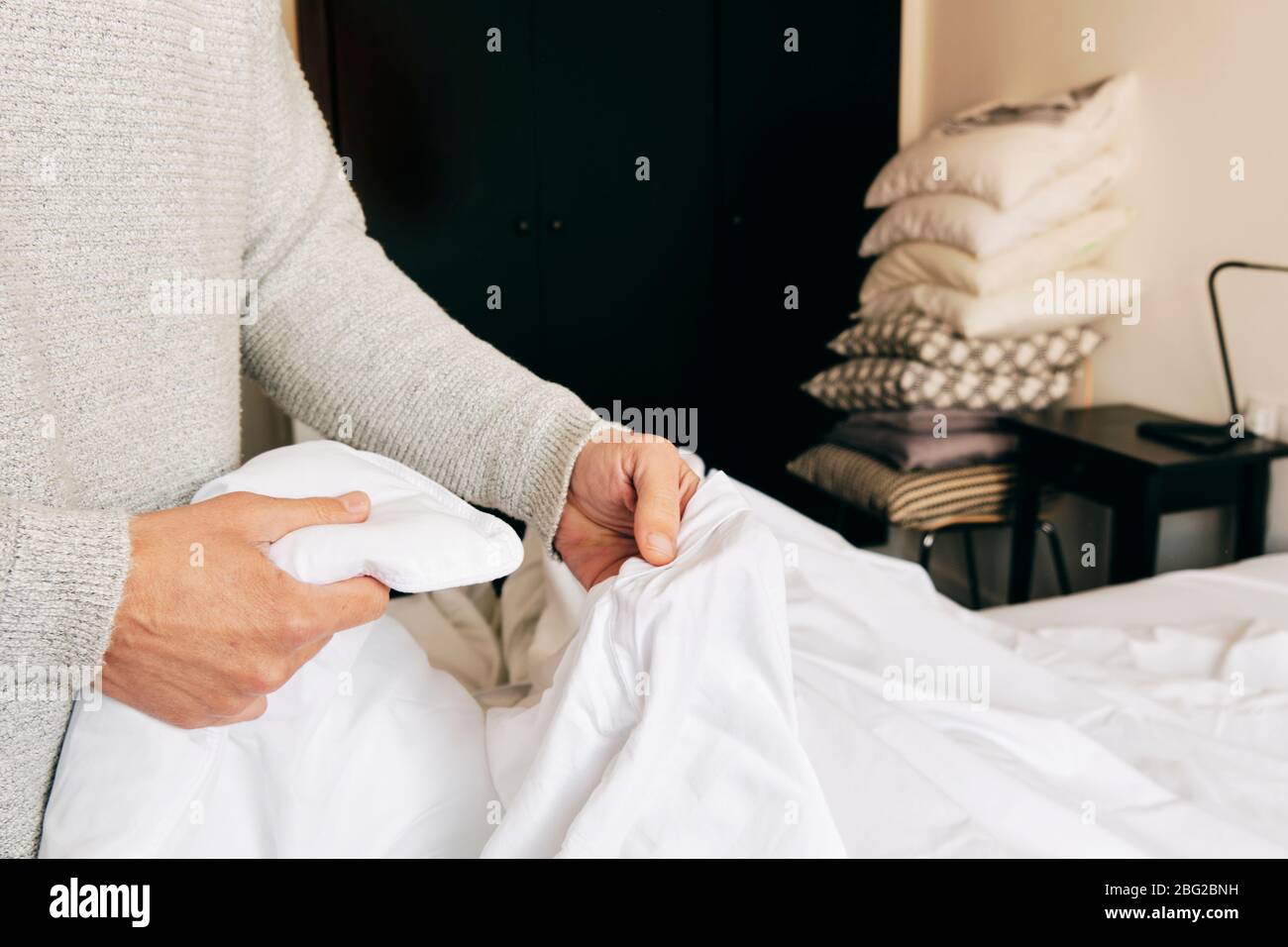 closeup of a young caucasian man inserting a duvet into a white duvet cover as he is making the bed Stock Photo