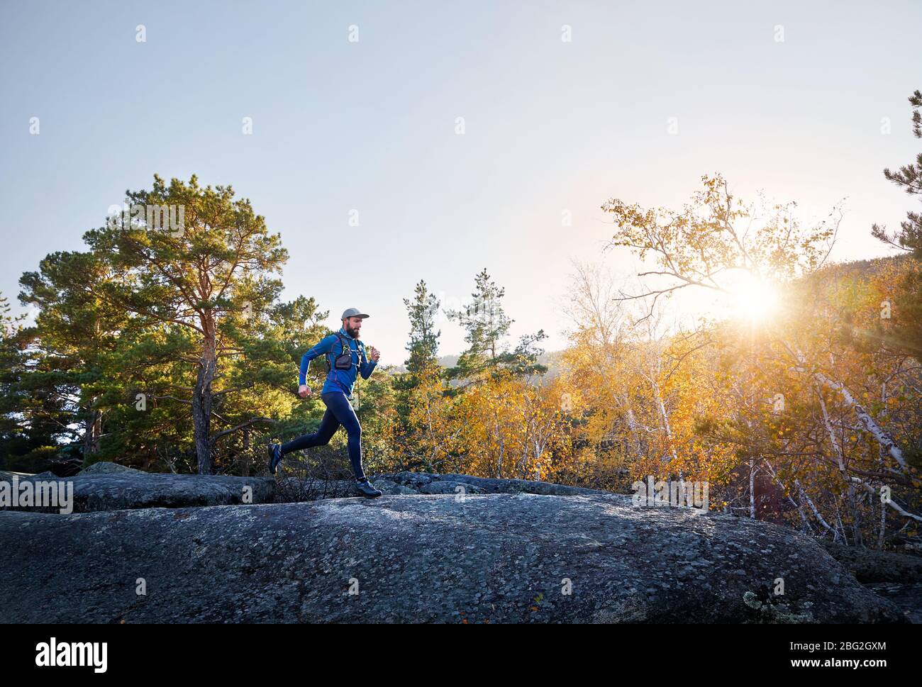 Runner athlete with beard in blue costume running on the trail in the mountains Stock Photo