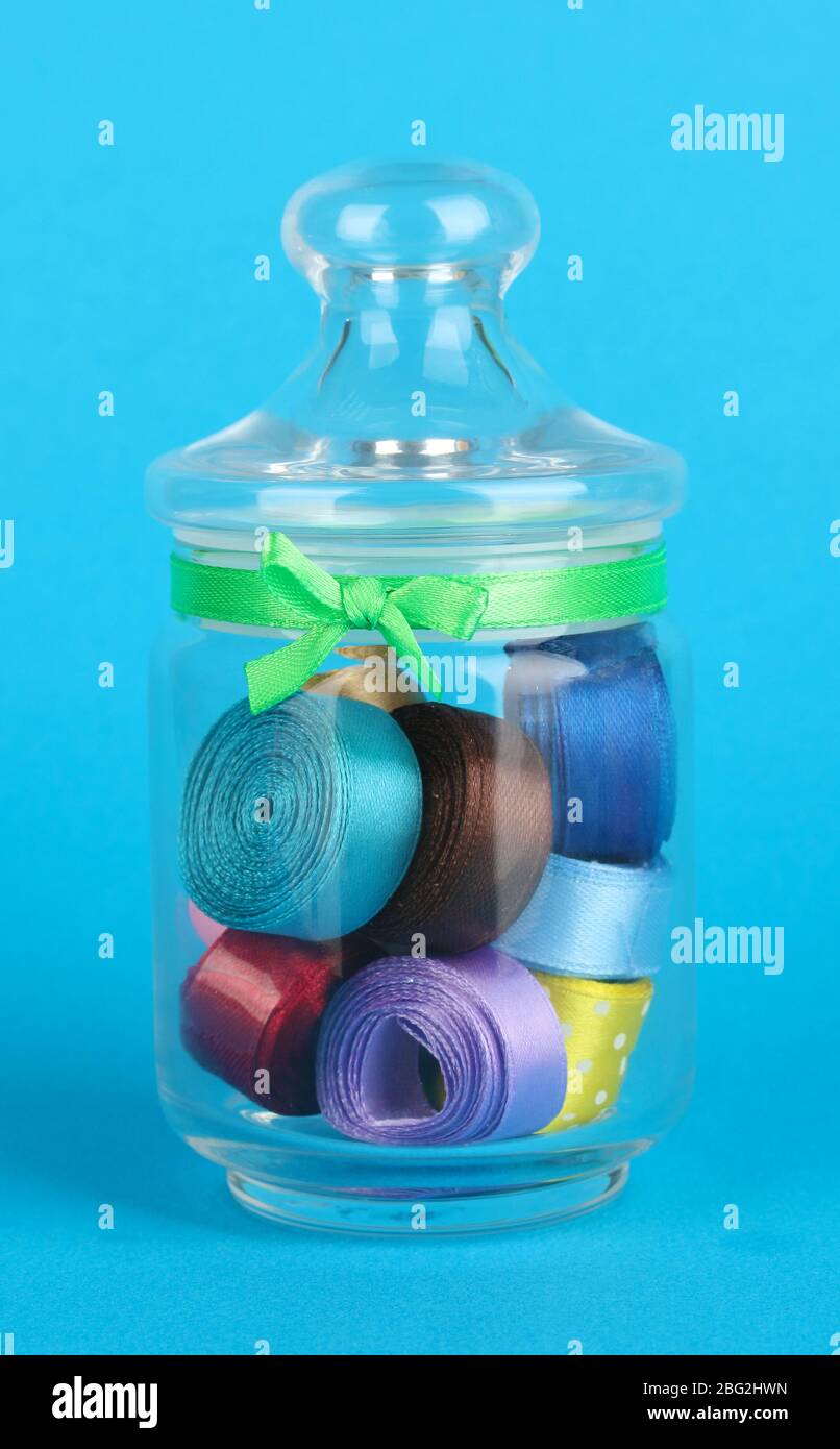 Glass jar containing various colored ribbons on blue background Stock ...