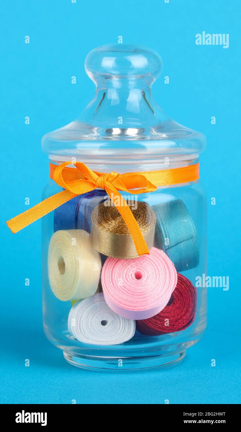 Glass jar containing various colored ribbons on blue background Stock ...