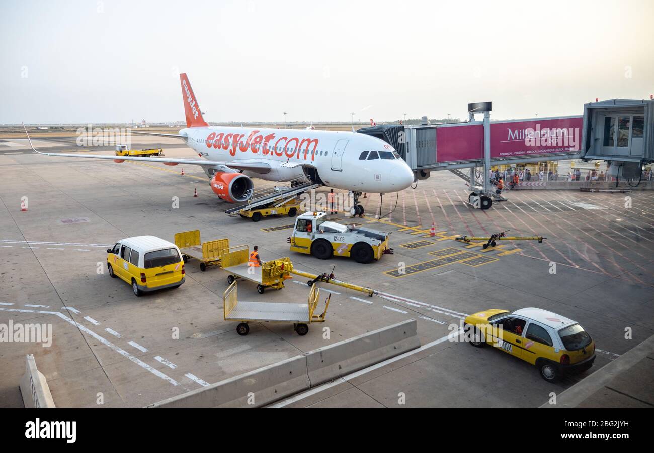 An EasyJet airplane standing at a gate at Faro International Airport, Portugal, with baggage handlers waiting to unload the luggage hold. Stock Photo