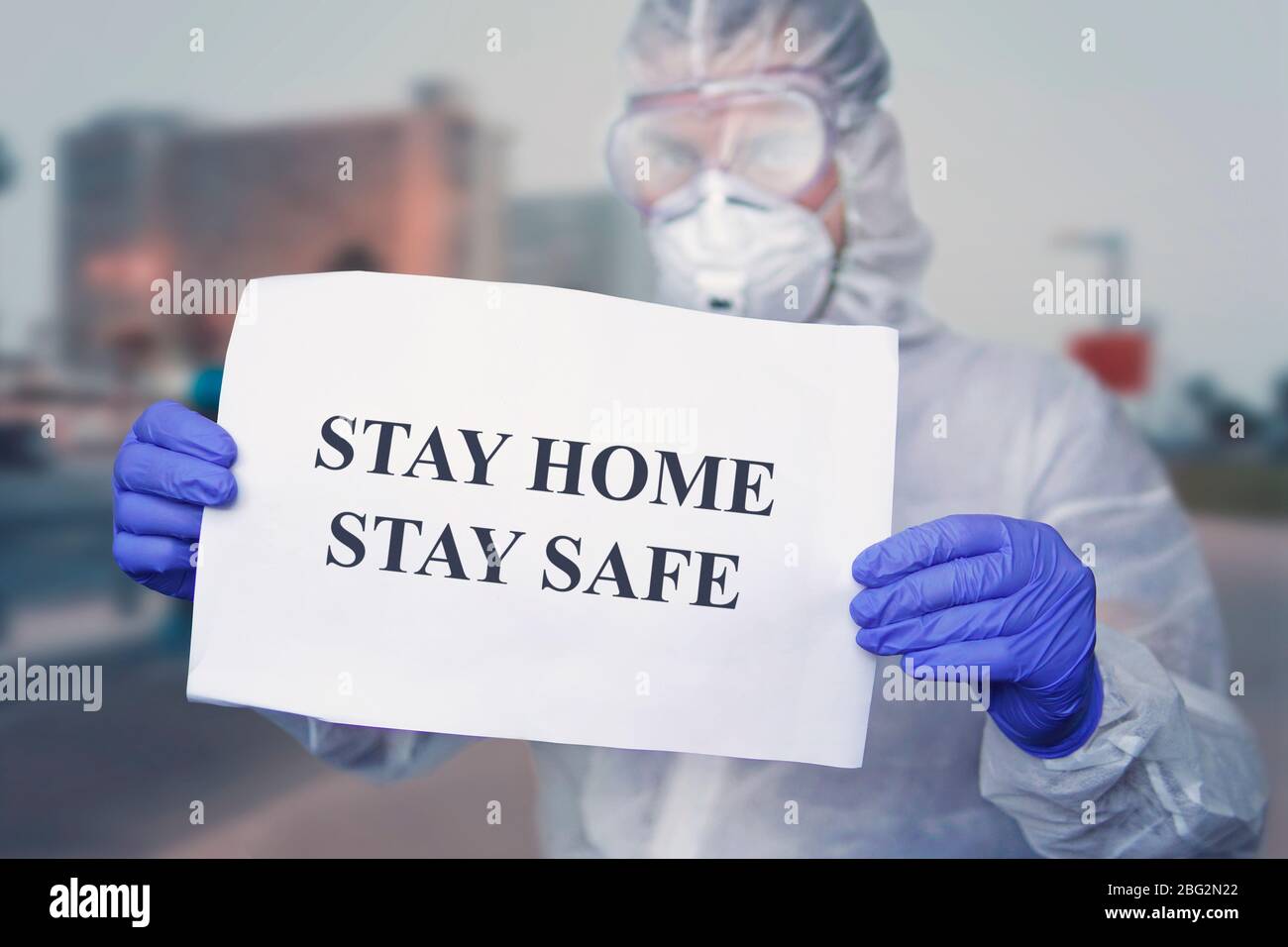 doctor in a protective suit at wear medical masks, holding paper with text STAY HOME STAY SAFE. stay at home in self-isolation policy campaign to cont Stock Photo