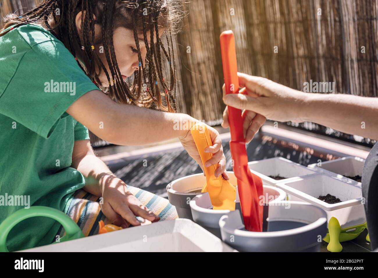 girl and her mother putting soil in the flower pots with a shovel at the balcony, hobbies at home, sustainable and ecological lifestyle concept Stock Photo