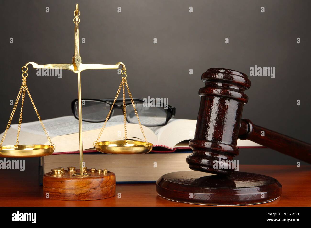 Wooden gavel, golden scales of justice and books on grey background ...