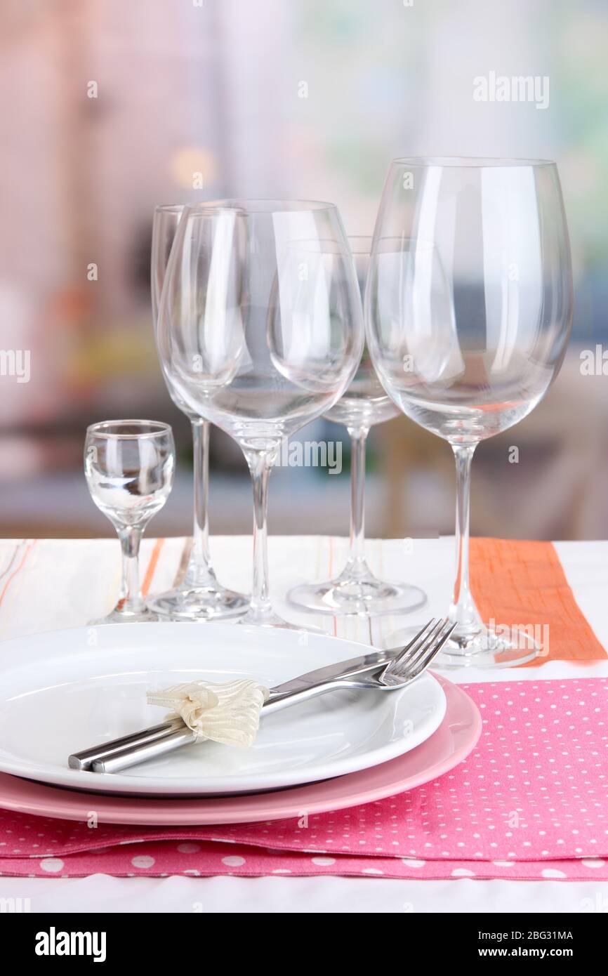 Table setting with glasses for different drinks on table on room