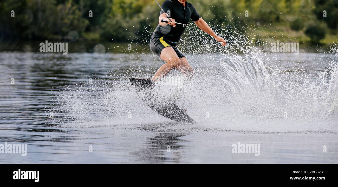 wakeboarder riding on lake behind boat in spray of water Stock Photo