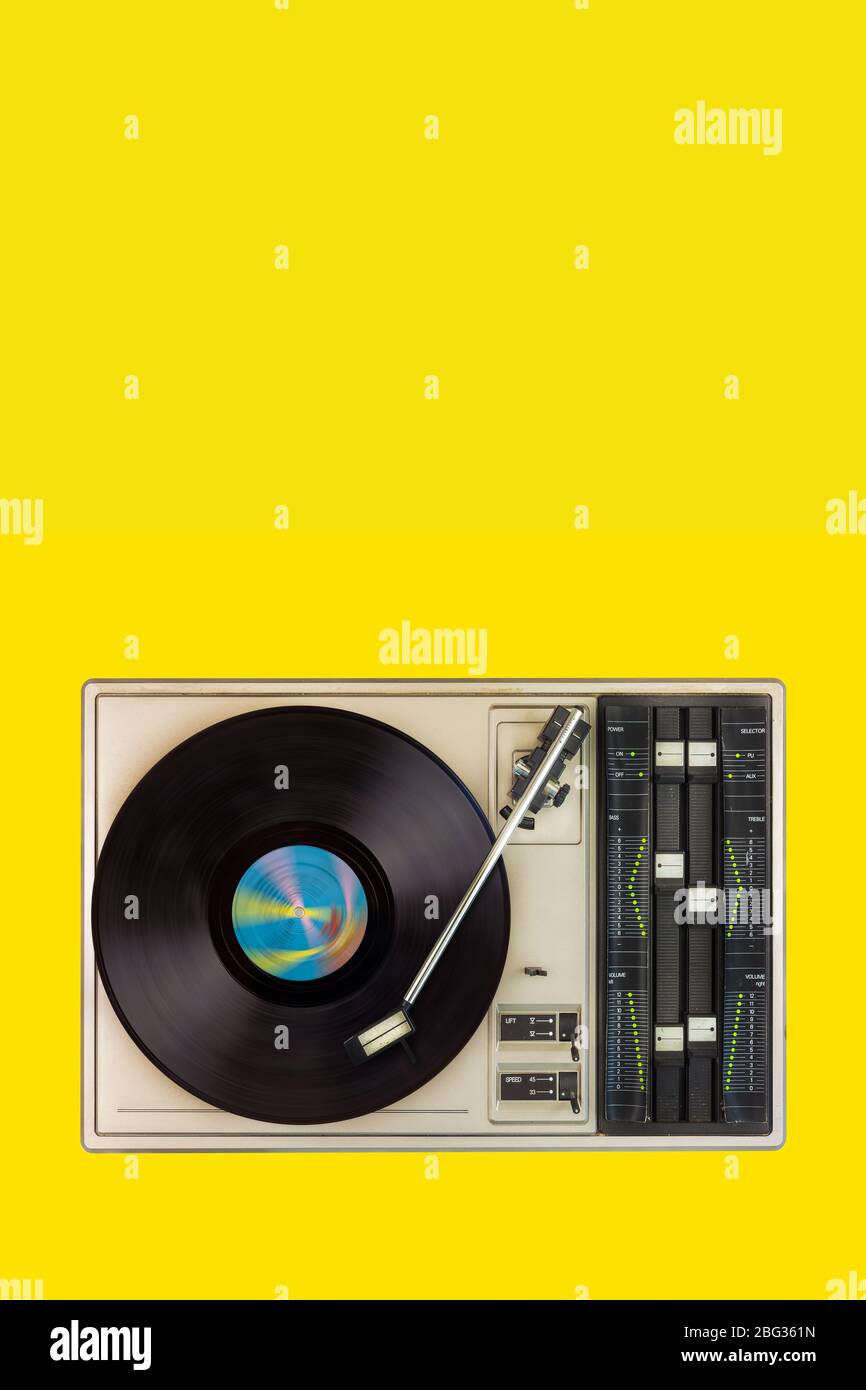 Vintage turntable with spinning record on a yellow blank background Stock Photo