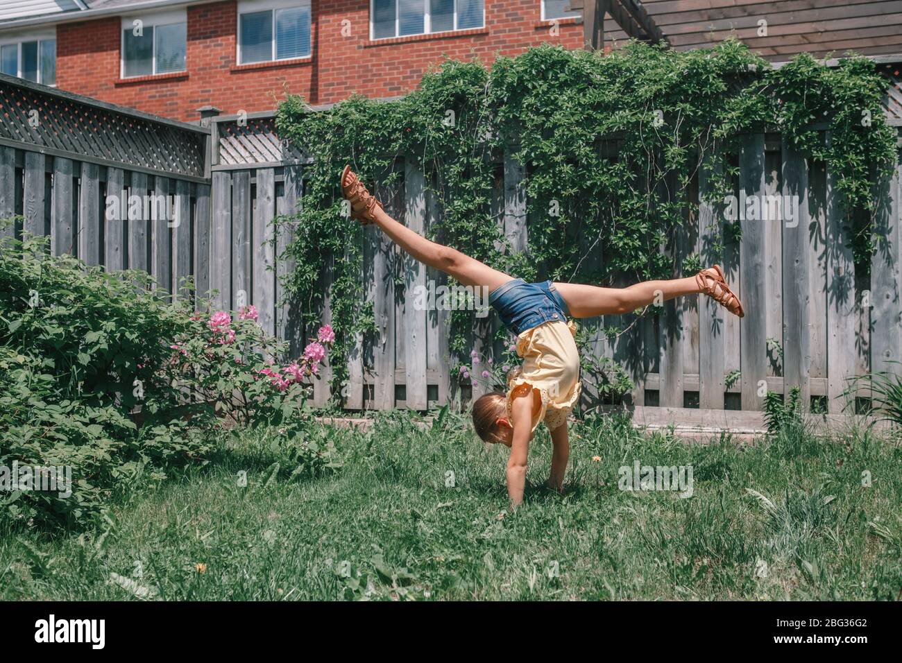 Funny child teenage girl doing cartwheel upside down stand. Excited joyful kid playing outdoor. Happy lifestyle childhood and freedom spirit. Stock Photo