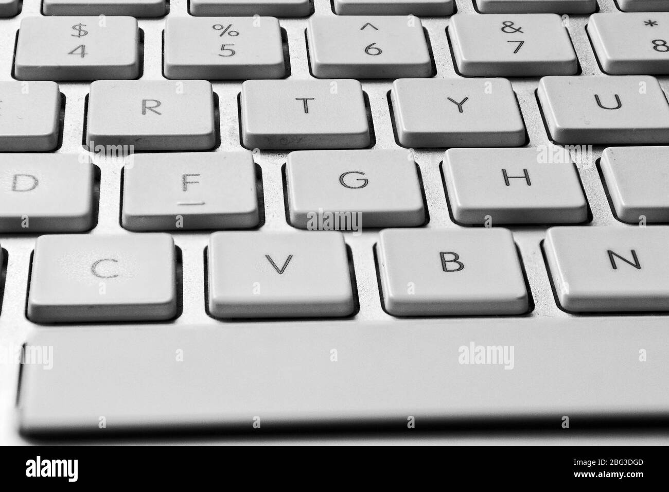 Close-up image of the middle section of a silver coloured computer keyboard clearly showing white keys 4, 5, 6, 7, R, T, Y, F, G, H, V, B and N with a Stock Photo