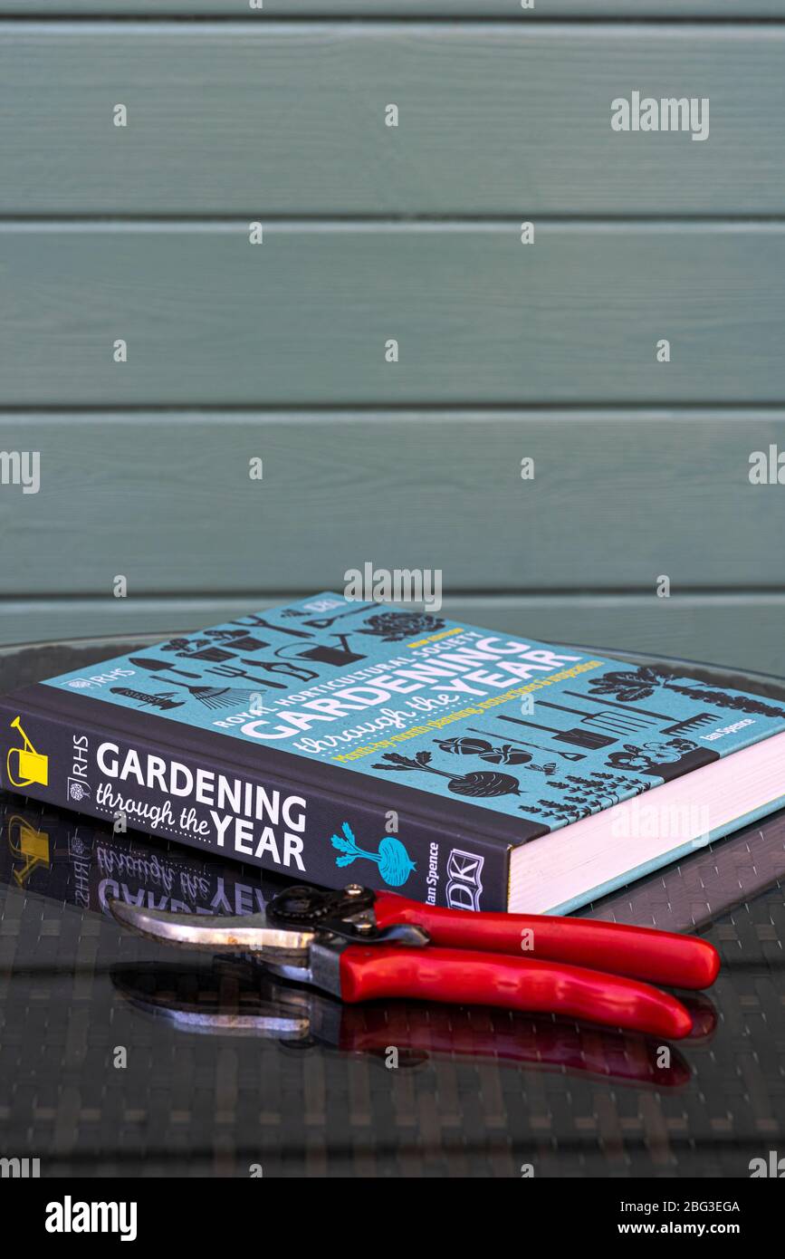 Gardening advice book on a glass topped table, outside a summer house. Stock Photo
