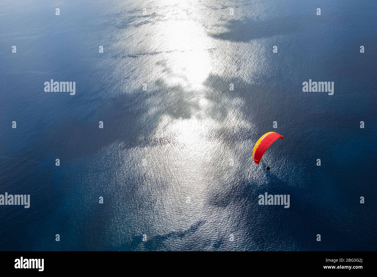 Paragliding in the sky. Flying over the Atlantic ocean with blue water in bright sunny day. Aerial view of paraglider on Madeira island, Portugal. Stock Photo