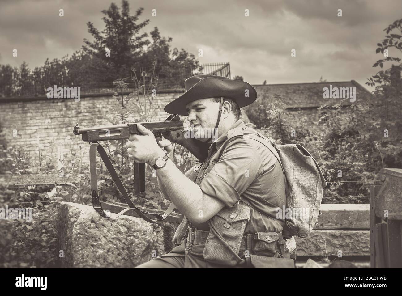 Old-fashioned, black and white close up of isolated soldier outdoors with gun taking aim at Black Country Museum, 1940s WWII wartime summer event, UK. Stock Photo