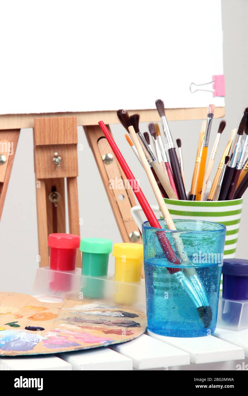 Wooden easel with clean paper and art supplies in room Stock Photo Alamy