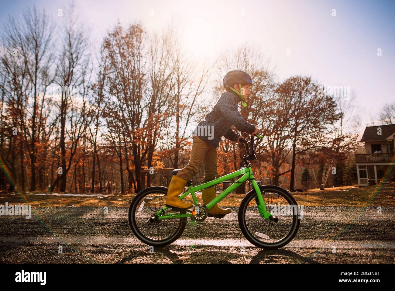Boy cycling along a wet road in springtime, USA Stock Photo
