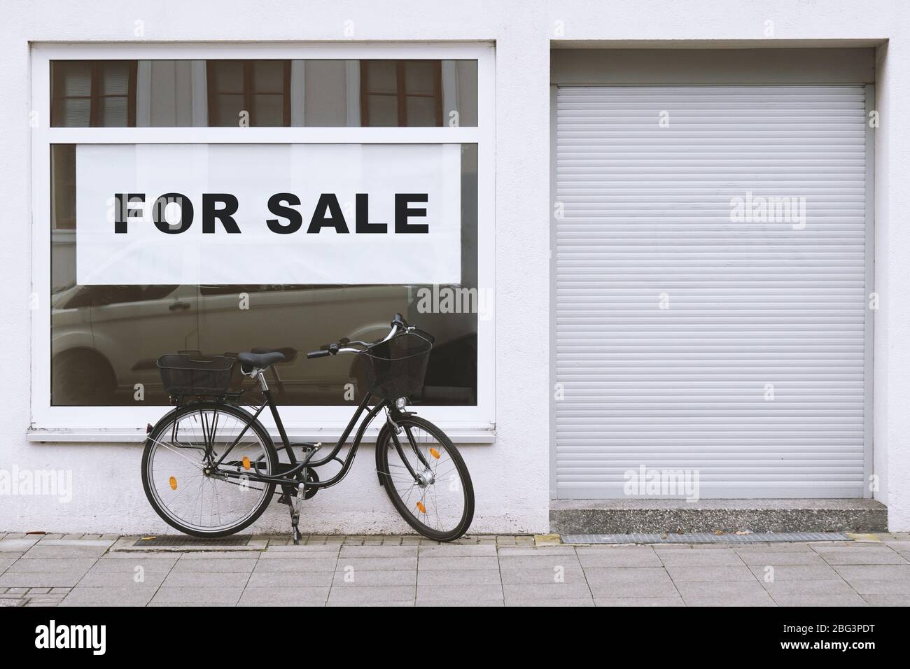 for sale sign in store window with bicycle parked outside - shop vacancy due to business closure - economy crisis and recession concept Stock Photo