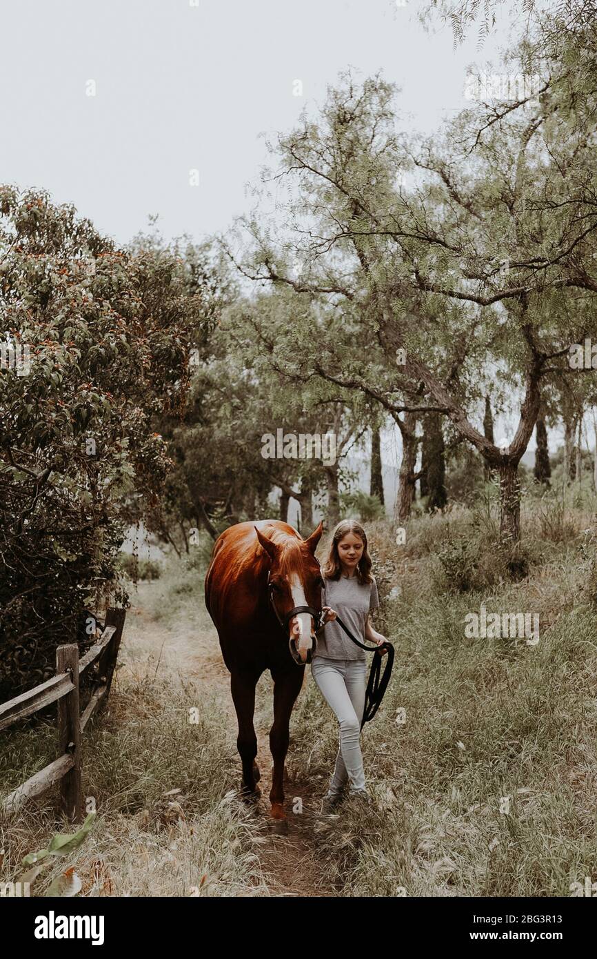 Girl walking through rural landscape with her horse, California, USA Stock Photo