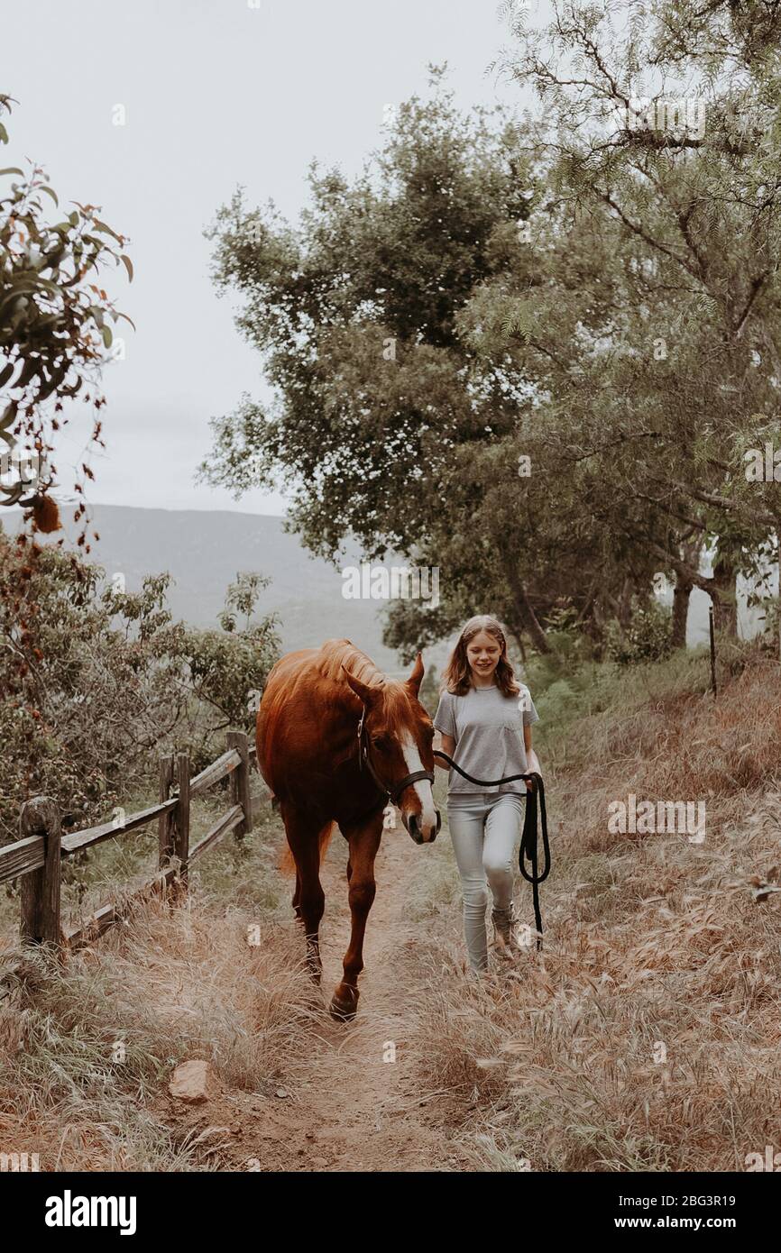 Girl walking through rural landscape with her horse, California, USA Stock Photo
