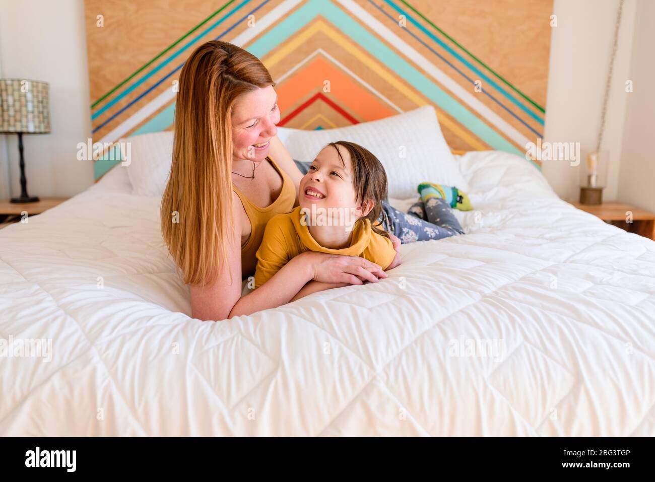 Mother and daughter lying on a bed laughing Stock Photo