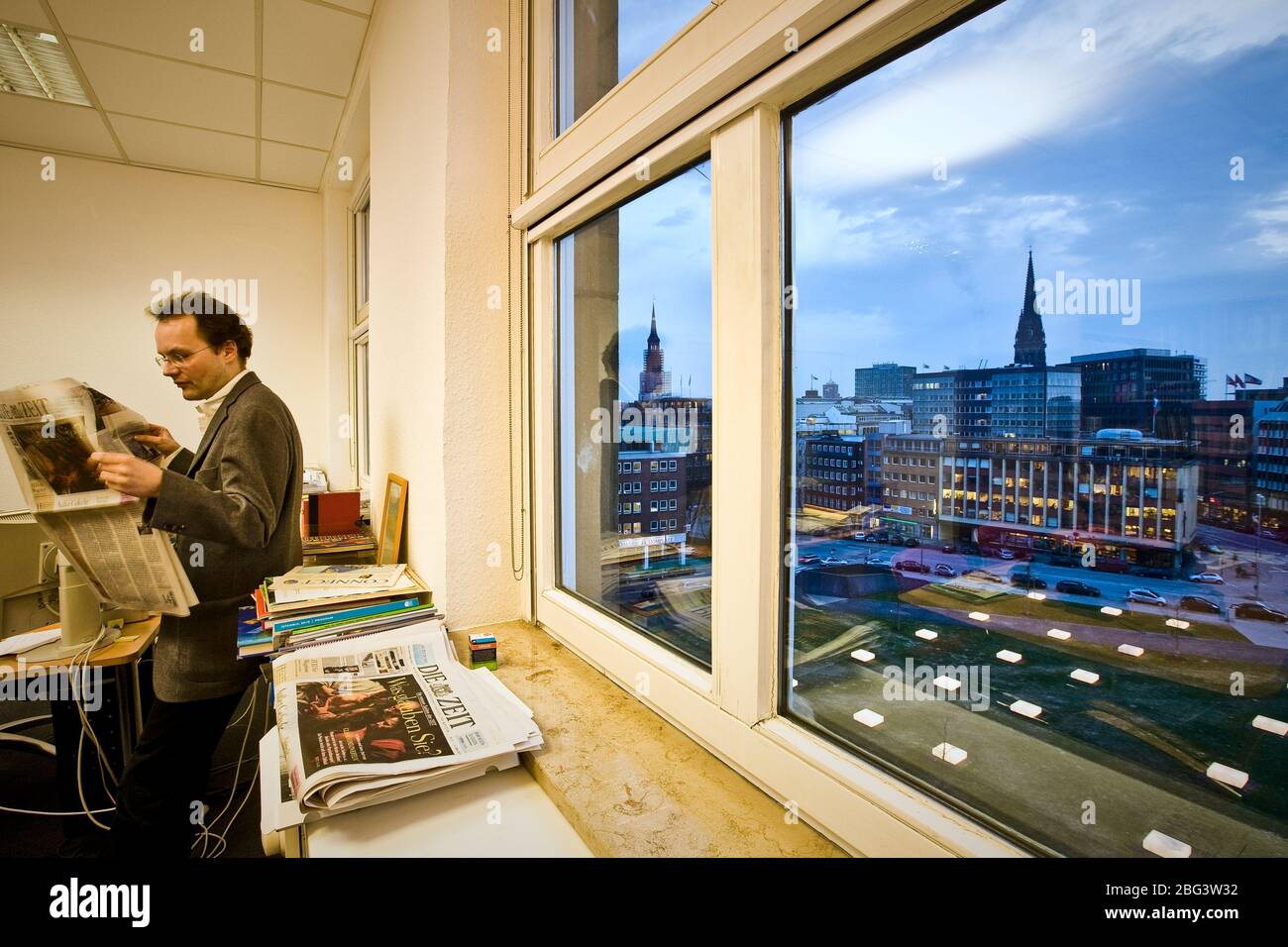 An editor of the weekly journal Die Zeit in his office with a view onto the illuminated Domplatz. In the Middle Ages at this point stood the Mariendom Stock Photo