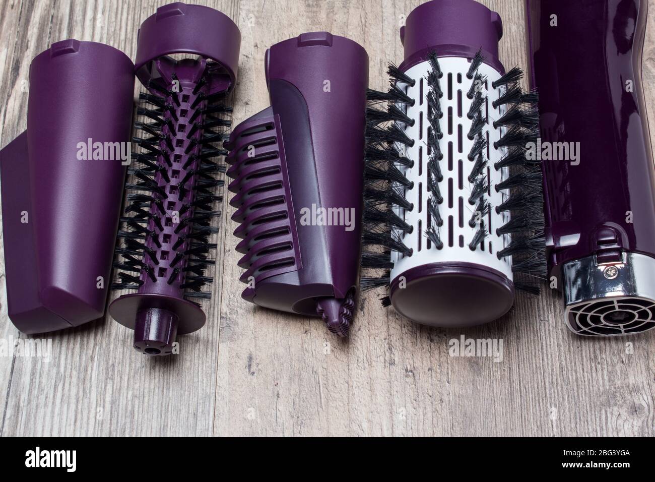 Set of hair dryer attachments on a wooden background. Curling iron