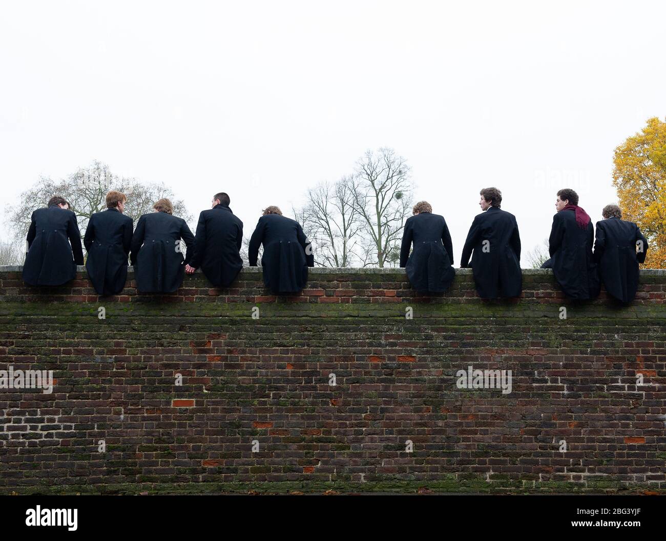 Eton, Windsor, Berkshire, UK. 20th November, 2010. Eton College boys sit on  top of a high wall built in 1717 next to the Eton College playing fields as  they watch their fellow