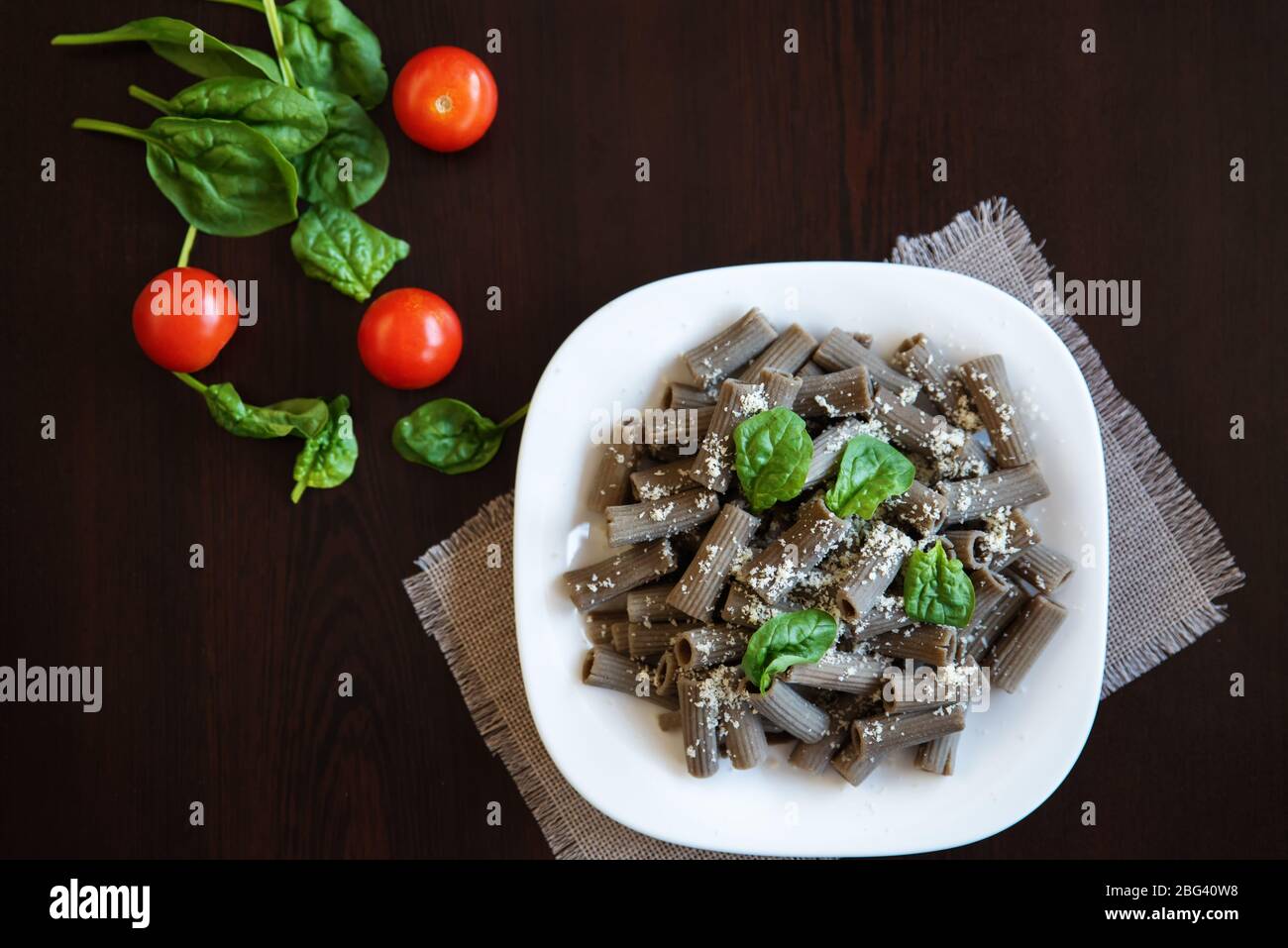 Lentil rigatoni pasta with spinach, tomato and parmesan Stock Photo