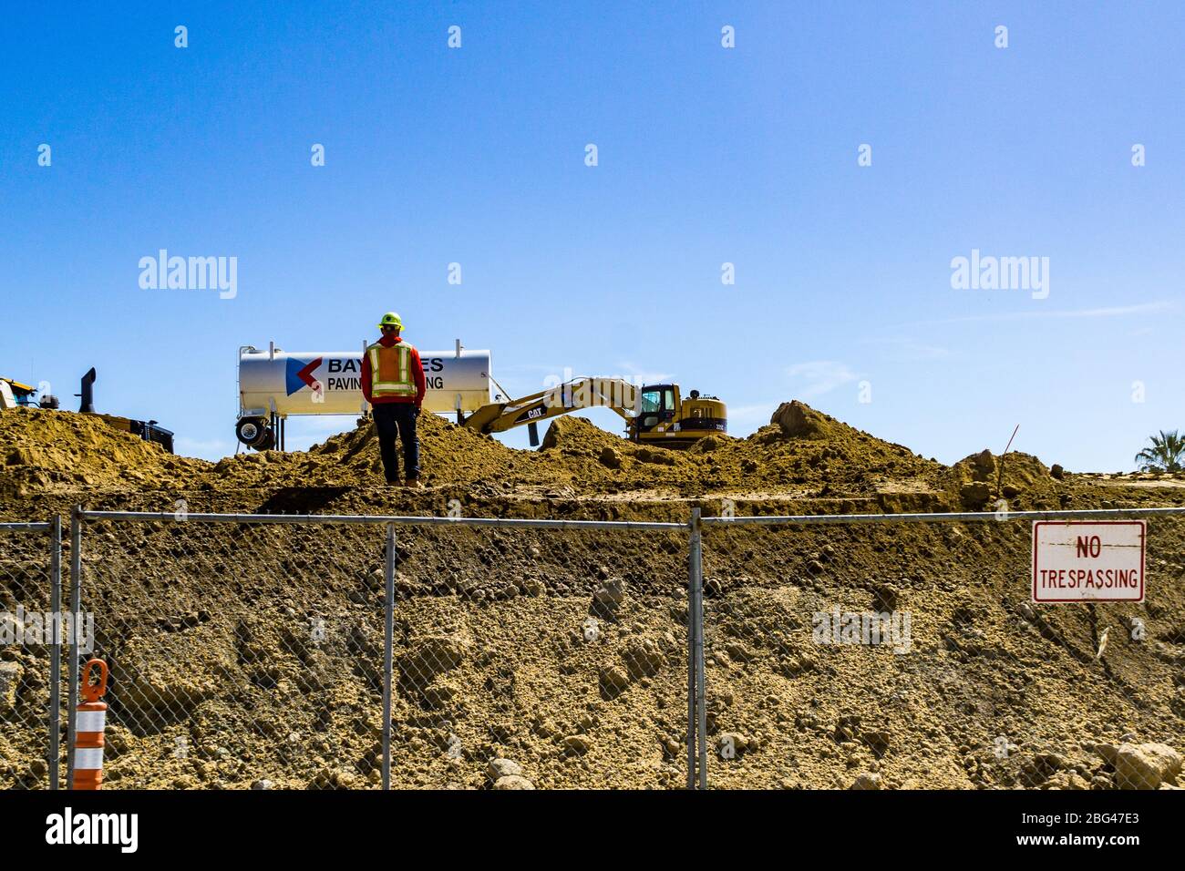 A construction spotter watches as heavy equipment works on a new