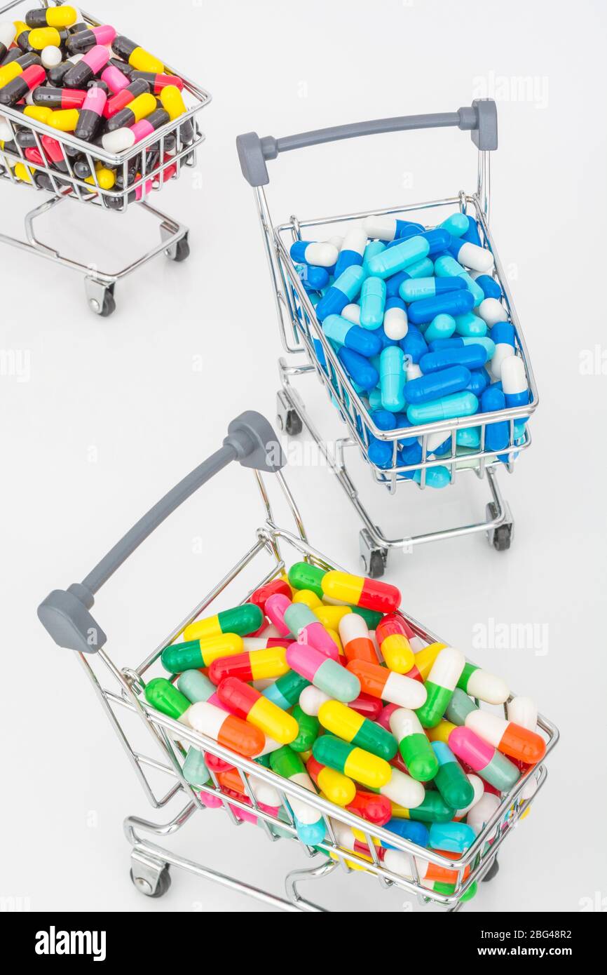 Mini shopping trolley full of colourful pills caplets. Metaphor Big