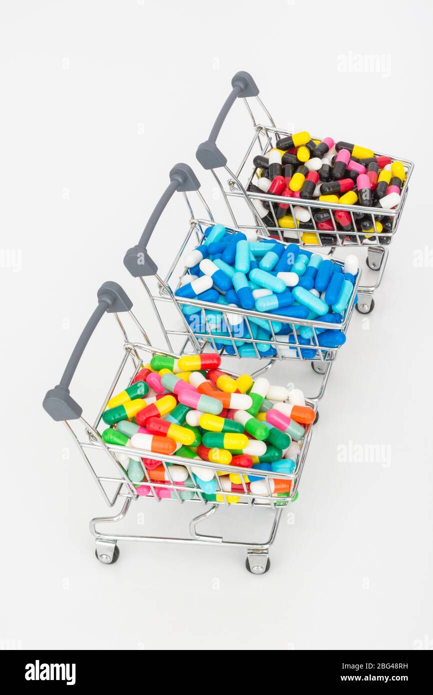 Mini shopping trolley full of colourful pills caplets. Metaphor Big