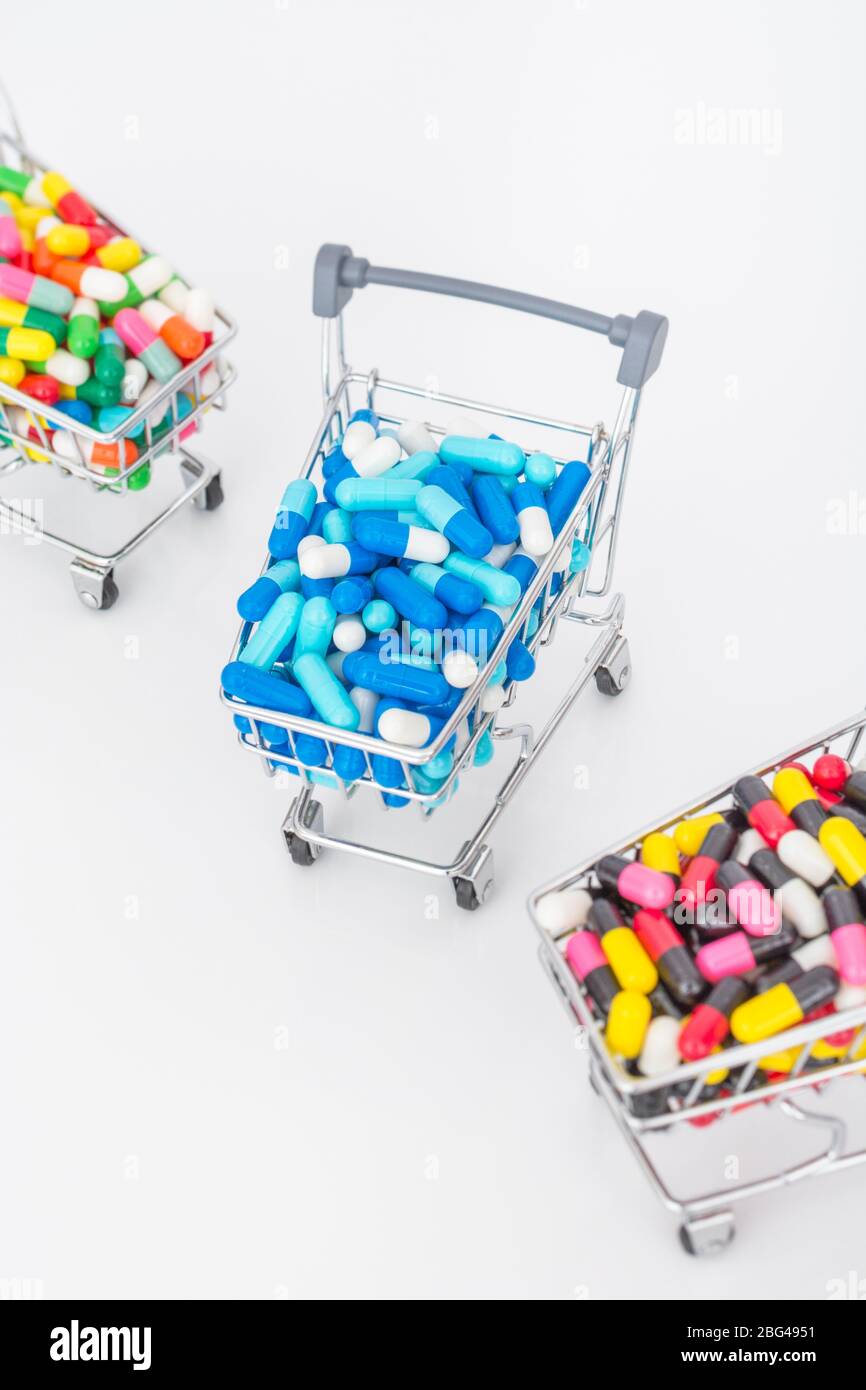Mini shopping trolley full of colourful pills caplets. Metaphor Big