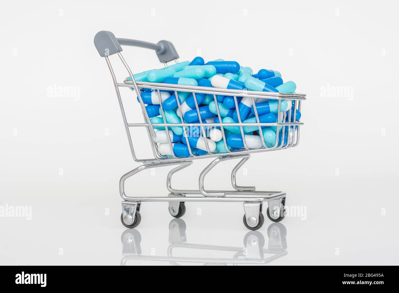Mini shopping trolley full of colourful pills caplets. Metaphor Big