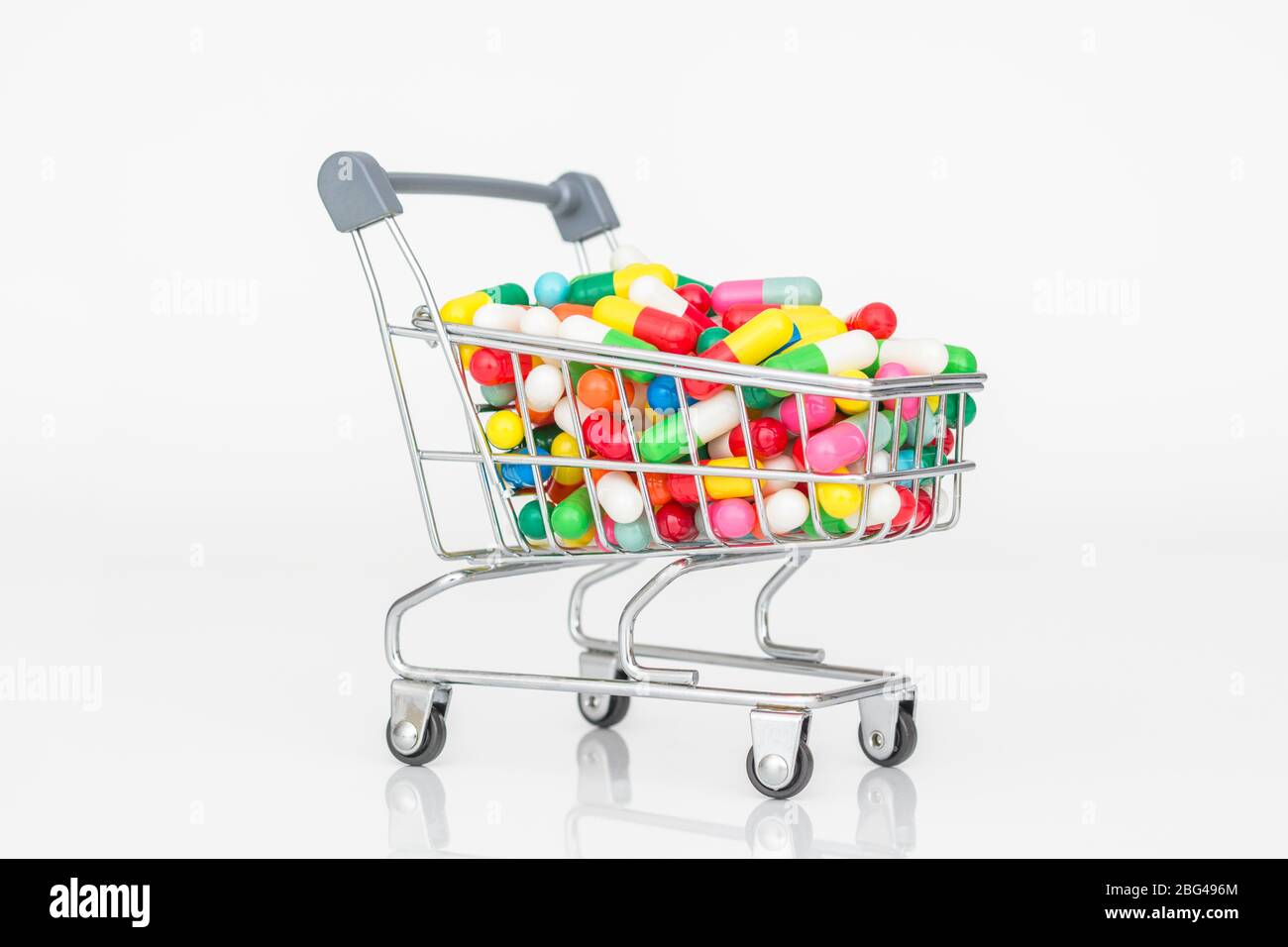 Mini shopping trolley full of colourful pills caplets. Metaphor Big