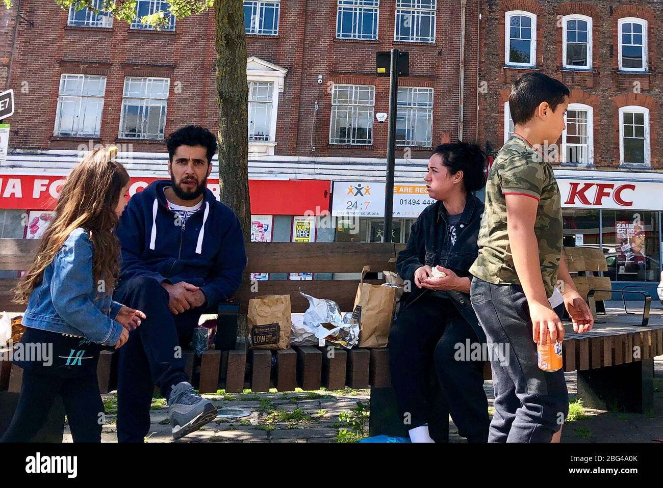 High UK. 20th Apr, 2020. A family sit on a bench and enjoy the hot weather while eating