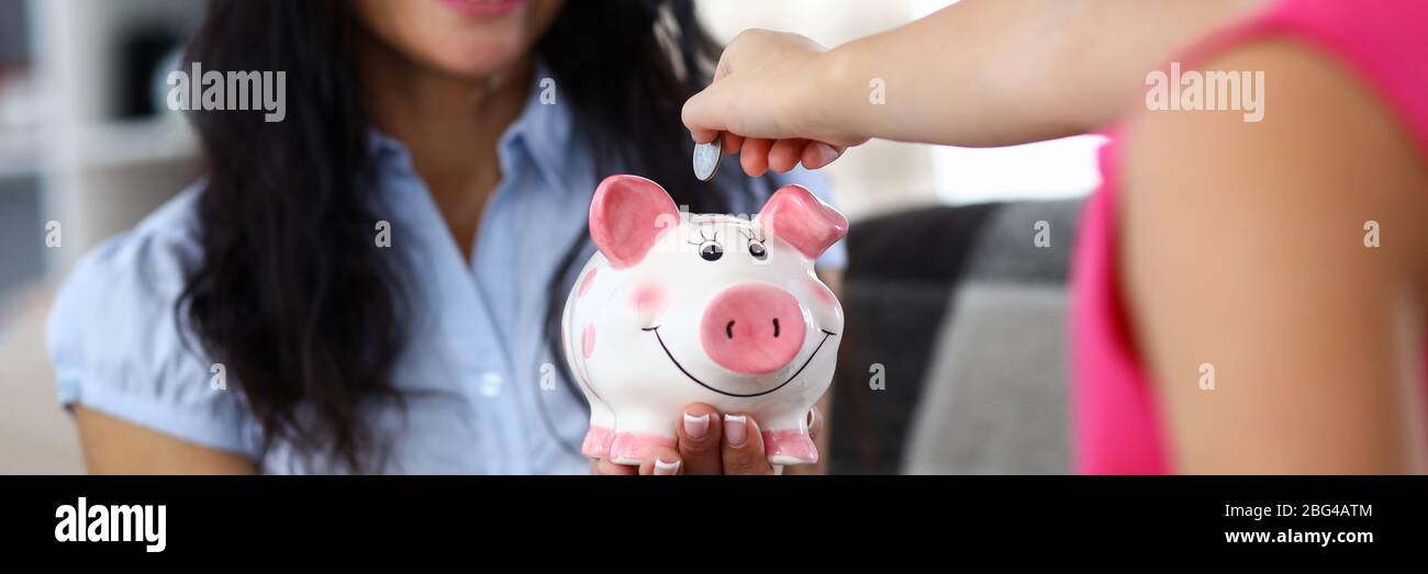 Girl throwing coin into moneybox Stock Photo