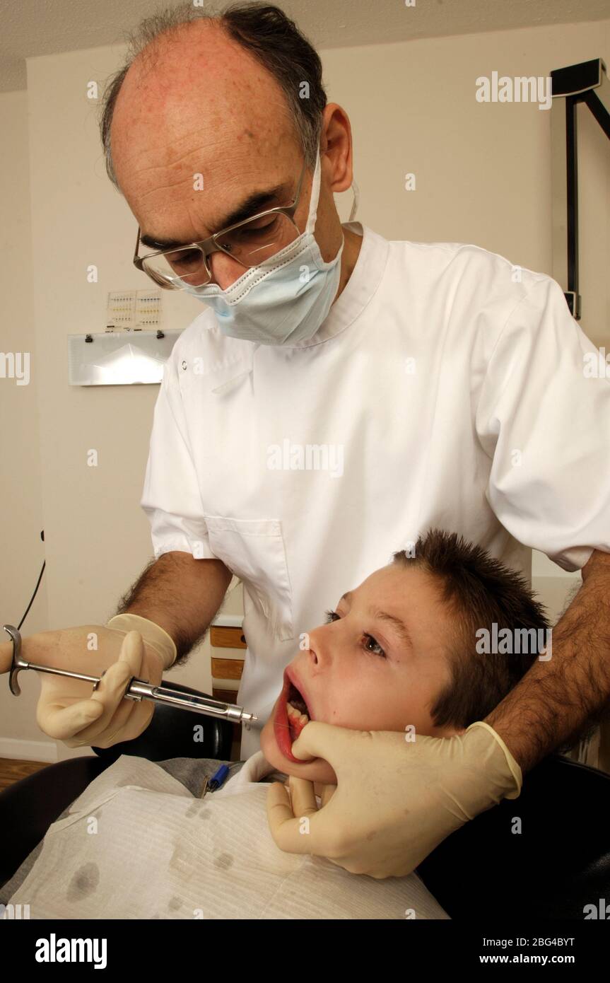 A dentist injects anaesthetic into the gums of a young male patient