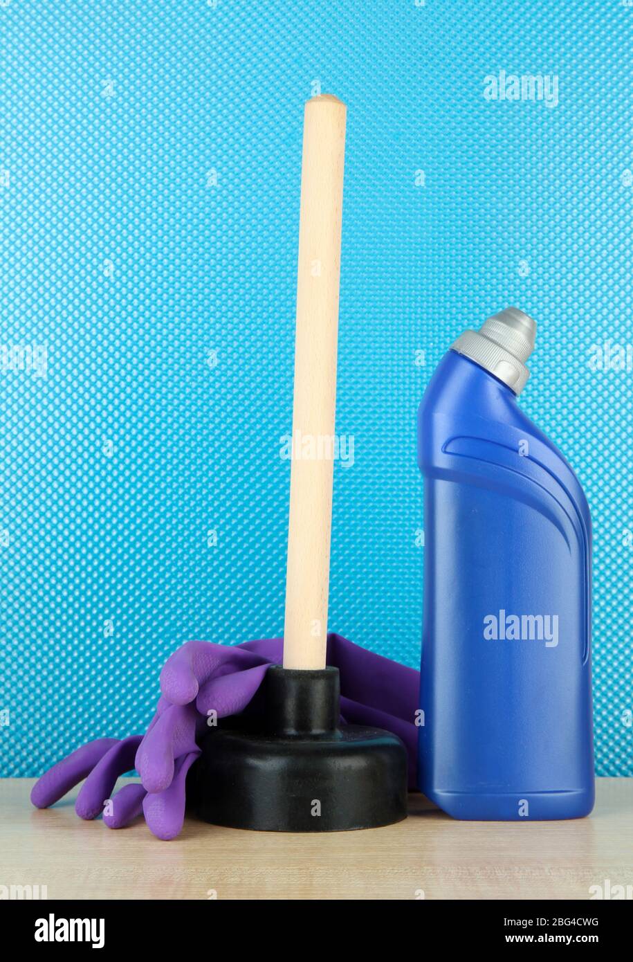 Toilet plunger, gloves and cleaner bottle on blue background Stock Photo