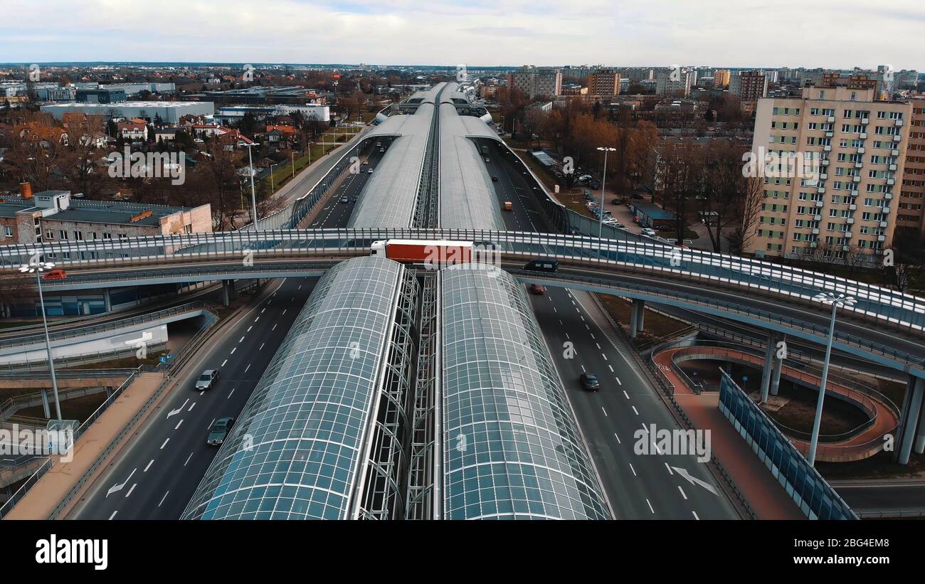 Warsaw, Poland, 03.20.2020. - The anti-noise glass tunnel and overpass Trasa Torunska highway in north-east Warsaw. Aerial wide dolly out shot Stock Photo