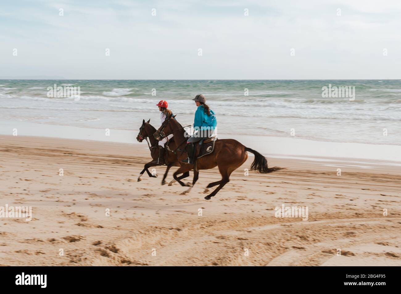 Two women riding Andalusian horses on the beach in Spain Stock Photo