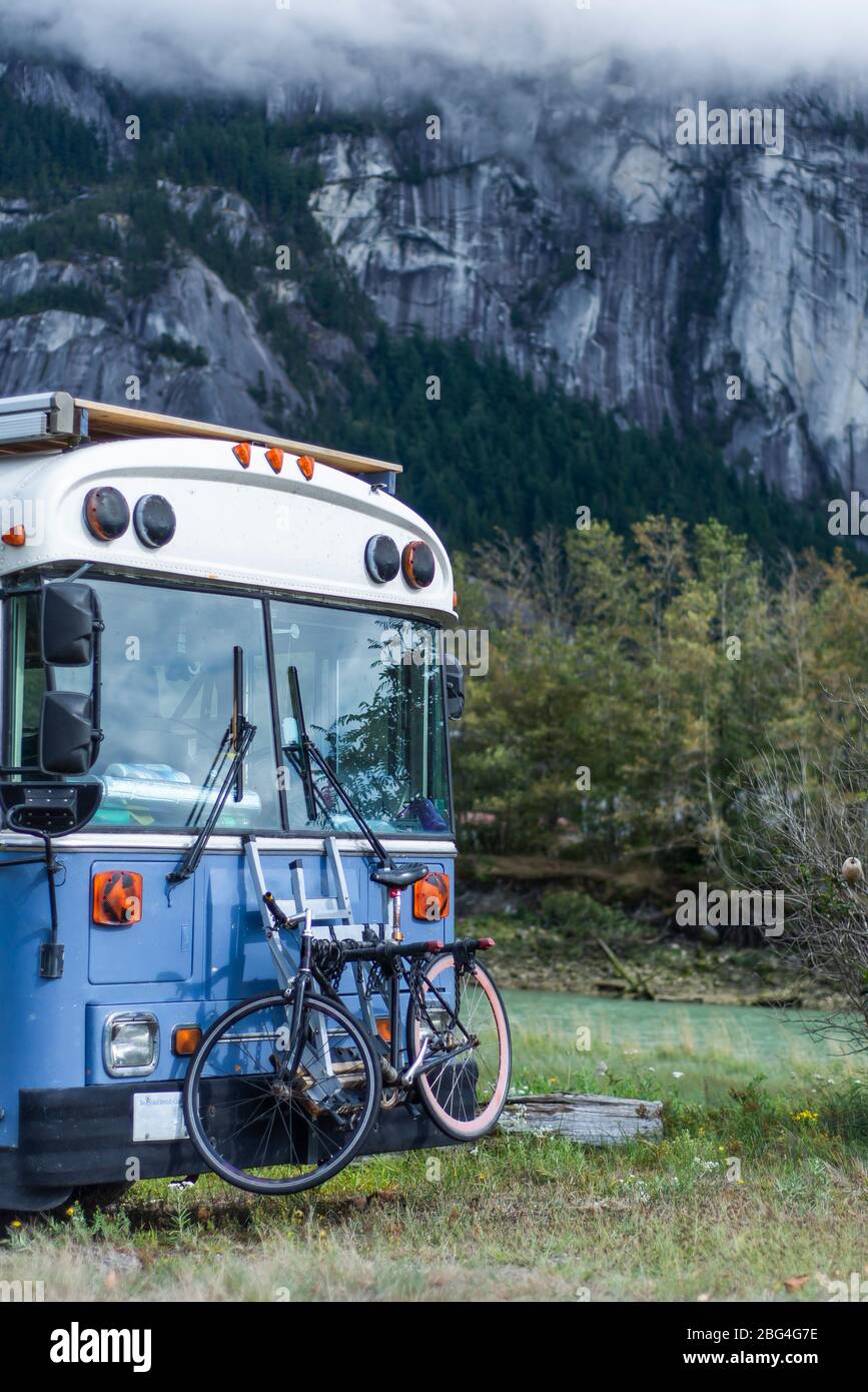 School bus converted parked front of Squamish Chief Mountain granite Stock Photo