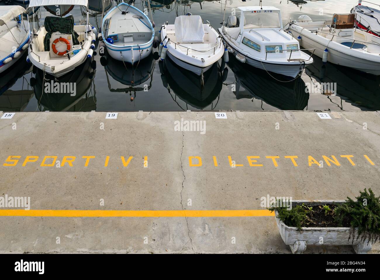 High angle view of the quay of the port of Sanremo with the painted sign of the Fishermen Amateur Association on the pavement and moored boats, Italy Stock Photo