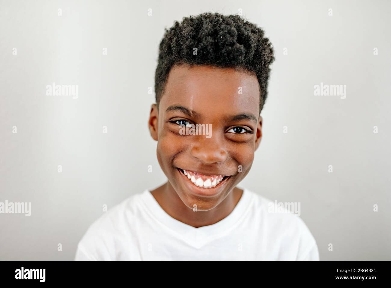 Headshot of sweet smiling black preteen boy wearing white t-shirt Stock Photo
