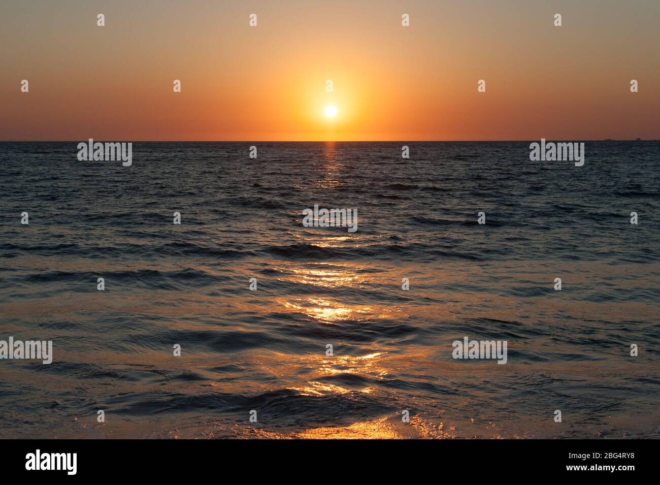 Orange sun setting over dark water in Mexico on Pacific Coast Stock Photo