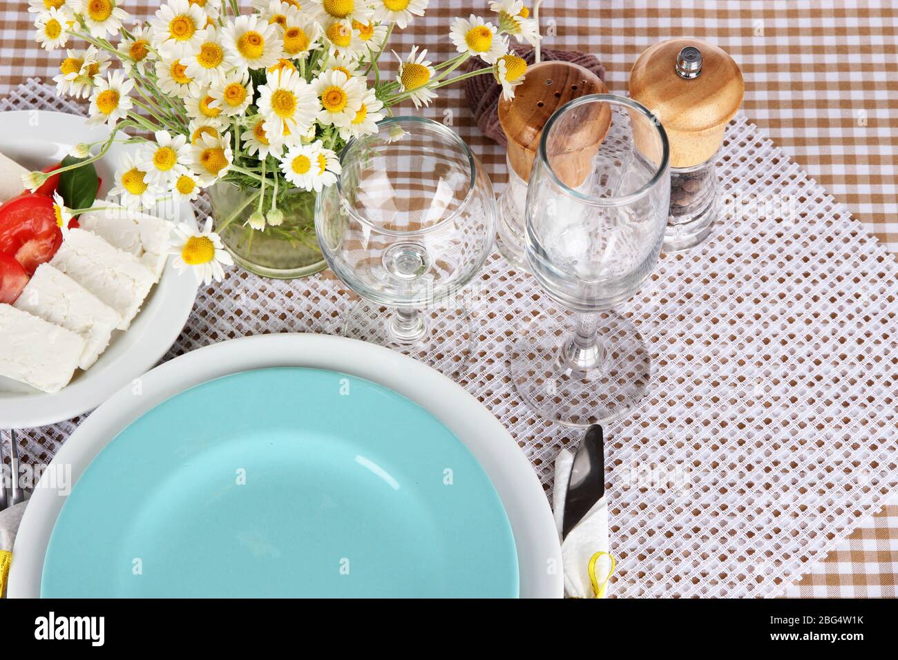 Table setting with chamomiles on checkered tablecloth Stock Photo
