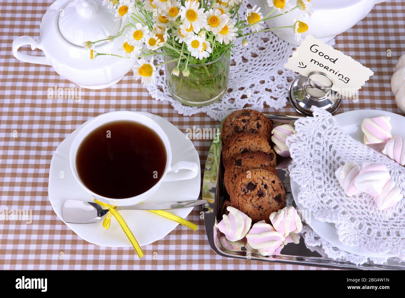 Table setting with chamomiles on checkered tablecloth Stock Photo